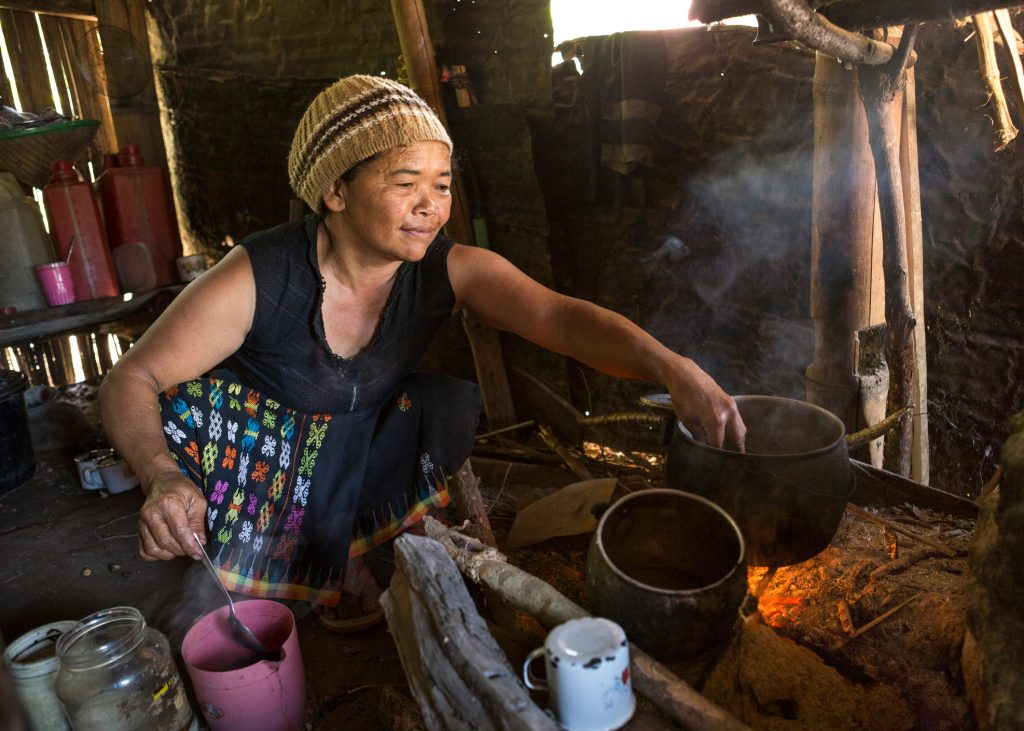 An old Asian lady is cooking with wood fire in her hut, Flores island in Indonesia.